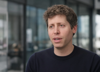 Sam Altman mid-interview, 3/4 front, navy sweater — the named CEO who ruled out a 2026 IPO.