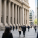 Wall Street plaza at midday with neoclassical exchange facade and a red market ticker in glass, as stocks trade soft and Treasury yields climb into Friday CPI.