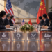 U.S. and China flags behind a conference table with rare earths, AI, tariffs and trade agenda markers