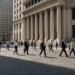 Office workers cross cobblestones at midday in front of the New York Stock Exchange as U.S. stocks hold near 1 percent.