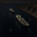 Two tankers transit a narrow arid strait at night under channel lights.