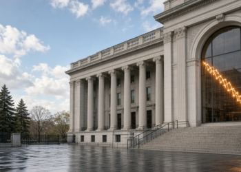 Classical U.S. finance facade on a wet plaza with a descending yield-curve glow in the arched window, as the 10-year retreats from a near-5% spike.
