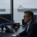 Energy trader at descending oil charts with tankers in gray harbor light, as WTI slips under $100 versus Thursday settles.