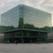 Pedestrians in a European plaza before a glass stock-exchange cube as regional indexes climb Friday.