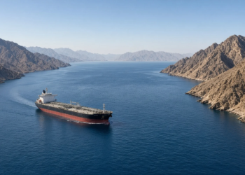 A crude tanker in a wide gulf lane between steep Musandam-style mountains (Strait of Hormuz).