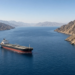 A crude tanker in a wide gulf lane between steep Musandam-style mountains (Strait of Hormuz).
