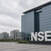 Monument NSE letters on a plaza in front of a modern exchange campus.