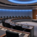 Empty circular international briefing chamber with podium and microphones, framing IAEA Board referral to the UN Security Council as diplomacy path, not enacted sanctions.