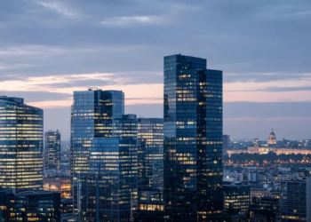 European glass office towers at blue hour, suggesting a large enterprise-software PE merger without deal-value text on image.