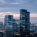 European glass office towers at blue hour, suggesting a large enterprise-software PE merger without deal-value text on image.