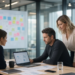 Team collaborating around a laptop beside a sticky-note whiteboard, suggesting a workplace software acquisition deal.