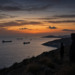 Observers on a Red Sea hillside overlooking commercial tankers at dusk, conveying Iran IRGC guidance around the Houthi Mocha campaign without combat imagery.