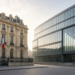 Paris ministry courtyard with a French flag and a descending growth chart on glass, reflecting France's cut to its 2026 GDP growth forecast.