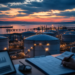 Oil storage terminal and tanker at dusk viewed past an analyst desk, suggesting a private production survey ahead of official oil-market reports.