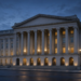 Neoclassical U.S. Treasury building facade at twilight with warm window lights, suggesting Treasury buyback and government-finance operations.
